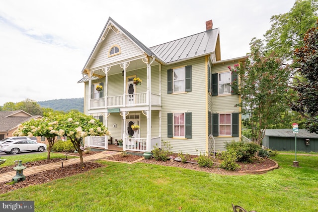 view of front of property featuring a balcony, covered porch, and a front lawn