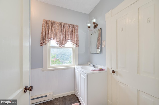 bathroom with a wainscoted wall, vanity, baseboard heating, and wood finished floors