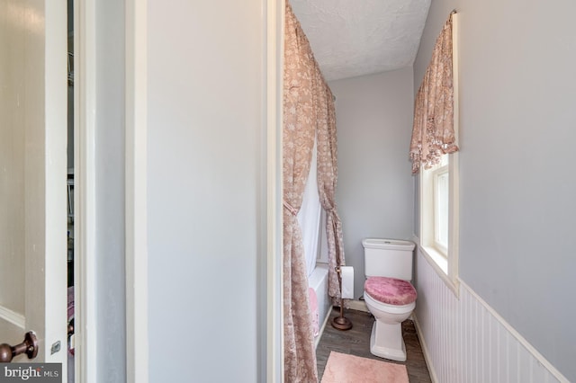 bathroom featuring shower / bath combo, toilet, hardwood / wood-style floors, and a textured ceiling