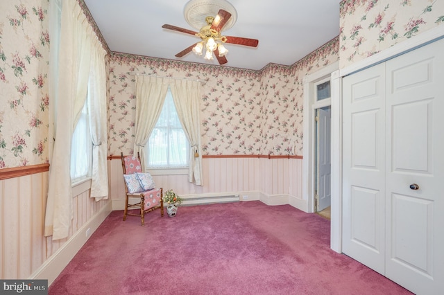 unfurnished room featuring ceiling fan, a baseboard radiator, carpet floors, wainscoting, and wallpapered walls