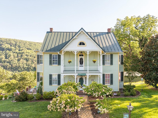 view of front of home featuring a balcony and a front lawn