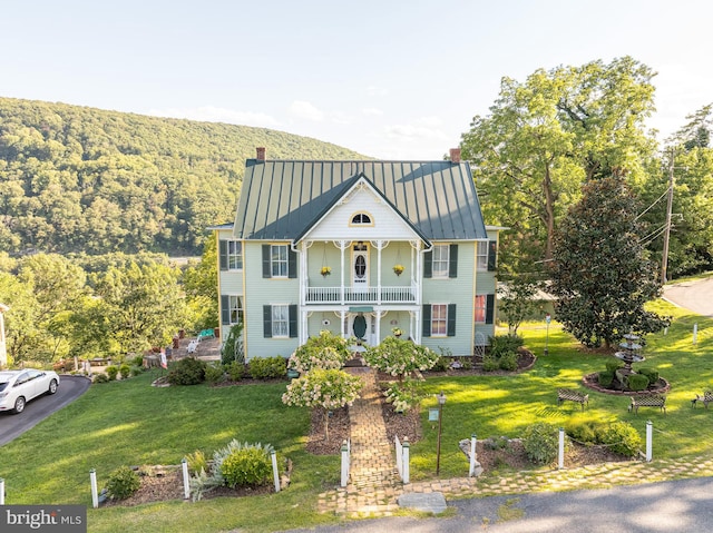 view of front of house featuring a balcony, covered porch, and a front lawn