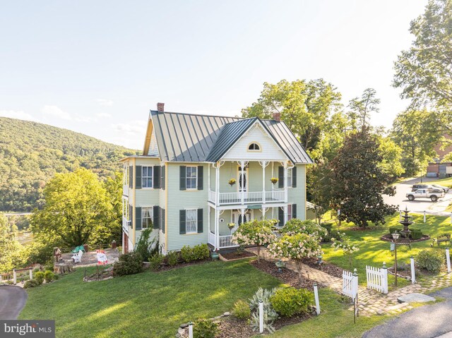 view of front facade with a balcony, covered porch, and a front lawn