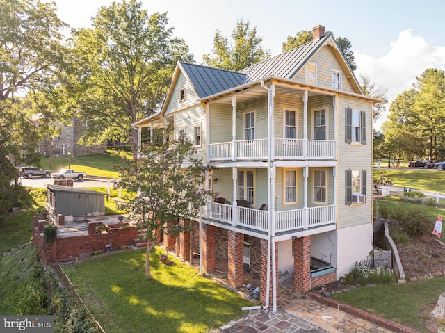 rear view of property featuring a balcony, a yard, and cooling unit