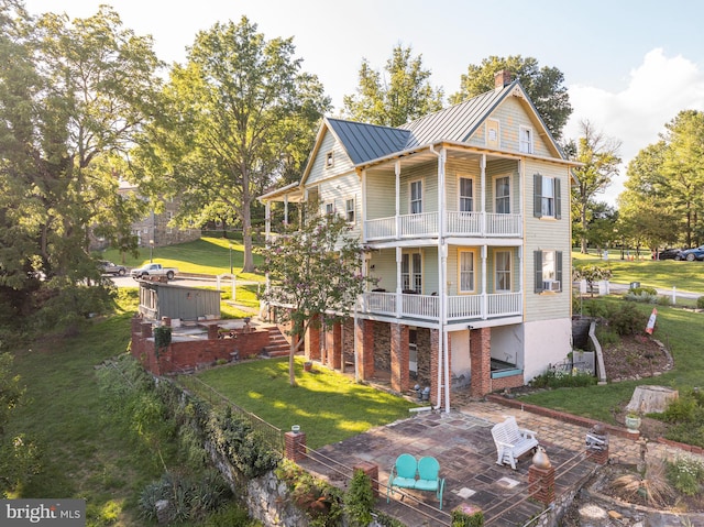 back of property featuring a balcony, a yard, and a patio area