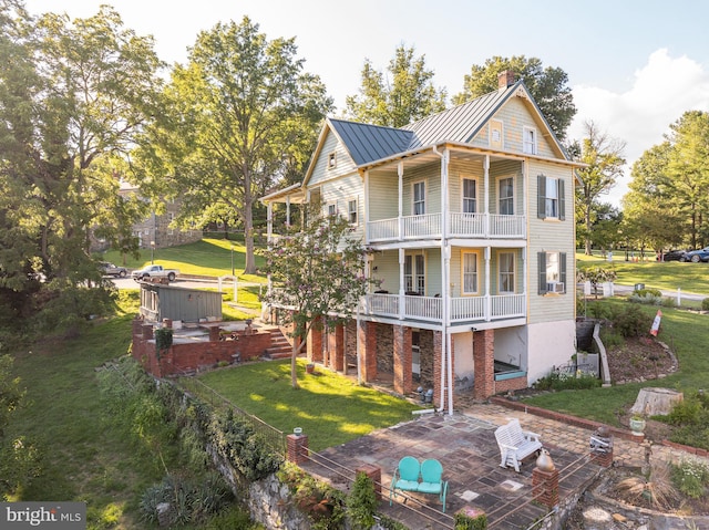 exterior space featuring a standing seam roof, a patio, a jacuzzi, a balcony, and a chimney