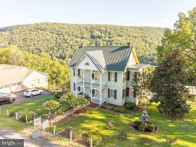 view of front facade with a front lawn and a balcony