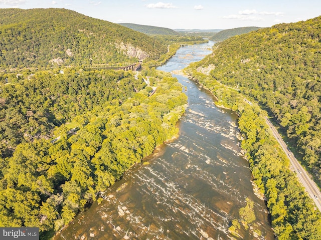 drone / aerial view with a forest view and a water and mountain view