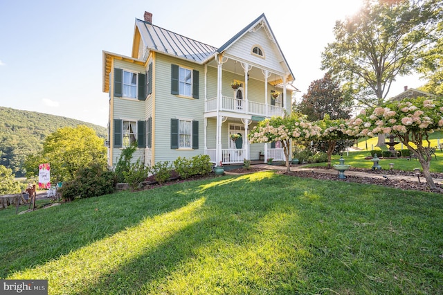 view of front of house featuring a front lawn, covered porch, and a balcony