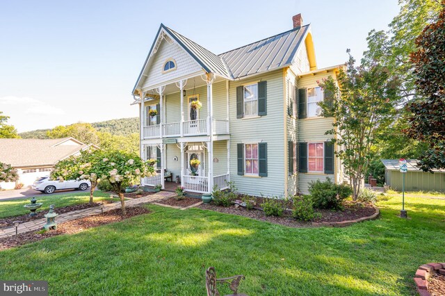 view of front of house with a balcony and a front lawn