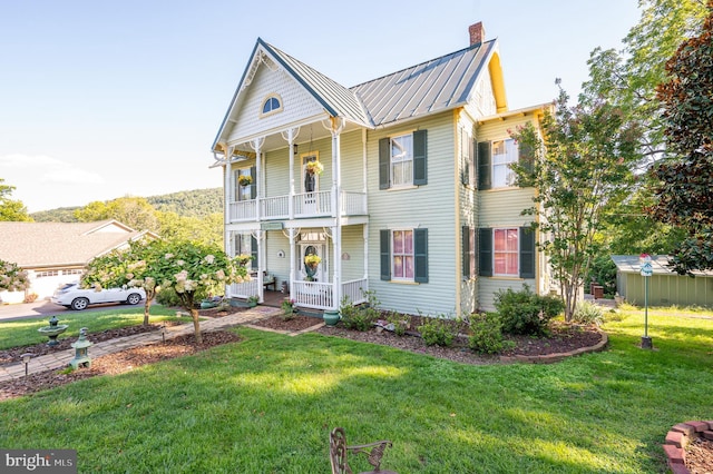 view of front facade featuring a chimney, a porch, a standing seam roof, metal roof, and a balcony