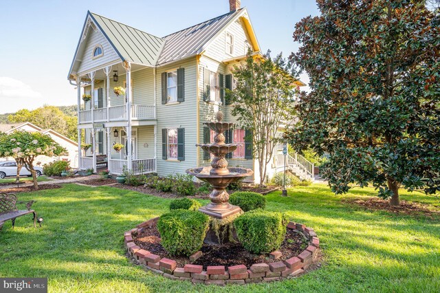 view of front of home with a balcony and a front yard