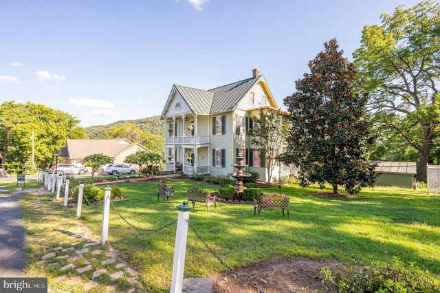 view of front of home featuring a balcony and a front lawn