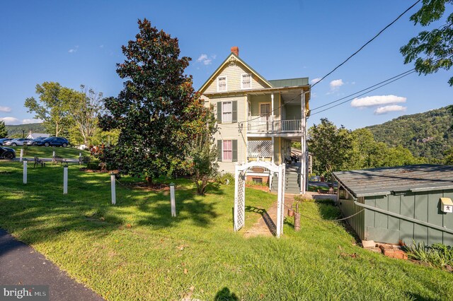 view of front of property featuring a balcony and a front lawn