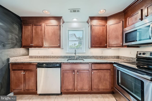 kitchen with light stone counters, appliances with stainless steel finishes, light tile patterned floors, and sink