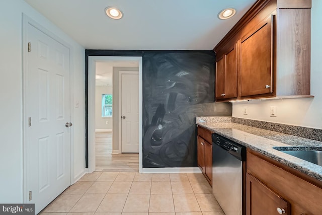 kitchen with light stone countertops, light tile patterned floors, and stainless steel dishwasher