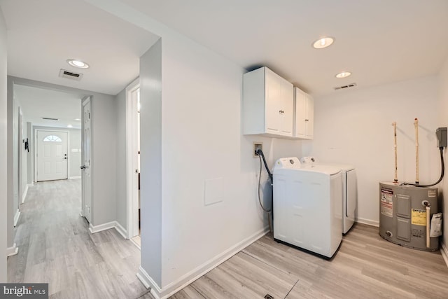 clothes washing area featuring cabinets, separate washer and dryer, water heater, and light wood-type flooring