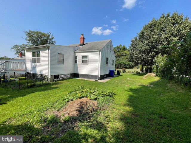 rear view of property featuring a yard and a wooden deck