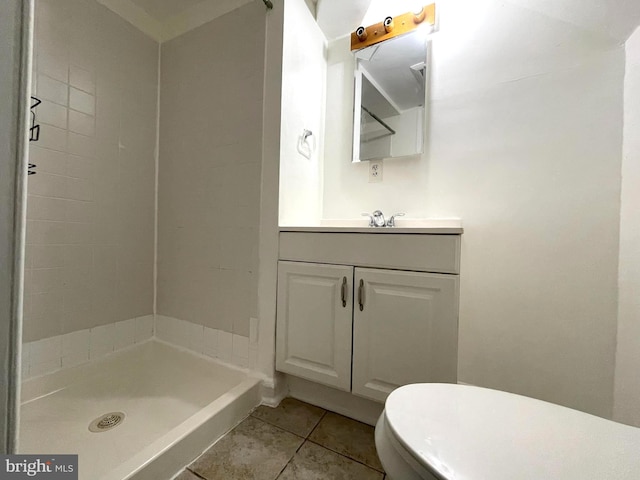 bathroom featuring vanity, tile patterned flooring, toilet, and a tile shower