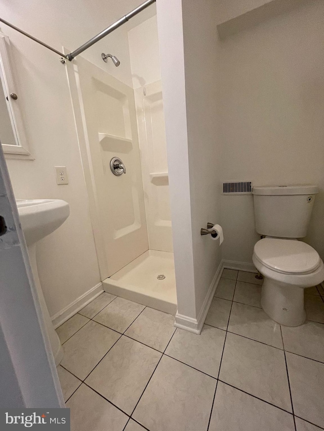 bathroom with tile patterned flooring, toilet, and walk in shower