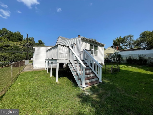 back of property with a wooden deck and a yard