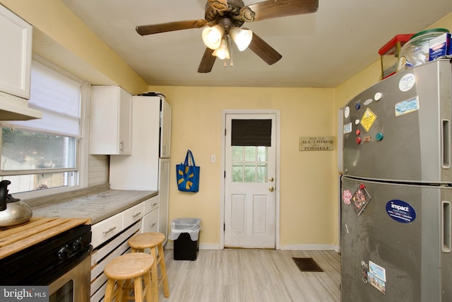 kitchen featuring light wood-type flooring, stainless steel fridge, ceiling fan, decorative backsplash, and white cabinets