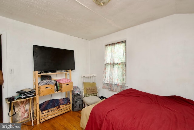 bedroom with wood-type flooring and vaulted ceiling