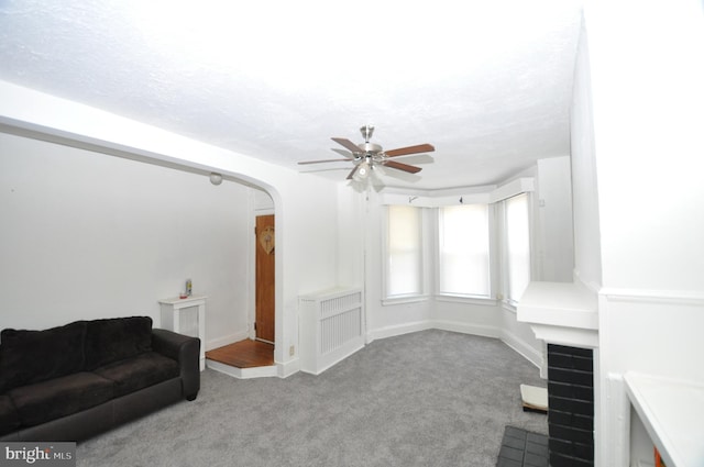 carpeted living room featuring ceiling fan and a textured ceiling