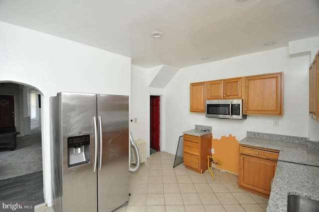 kitchen with appliances with stainless steel finishes, light stone counters, and light tile patterned floors