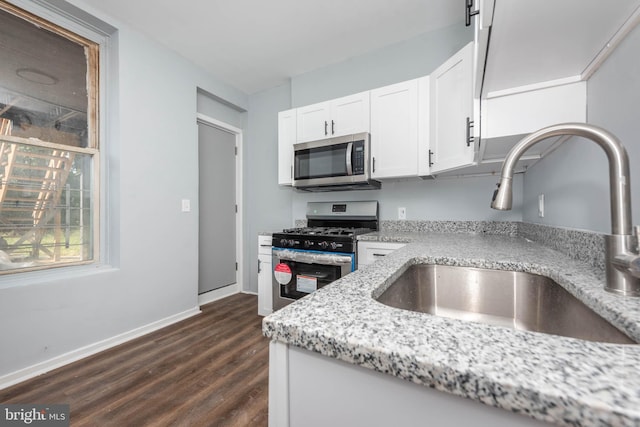 kitchen with sink, dark wood-type flooring, appliances with stainless steel finishes, white cabinetry, and light stone countertops