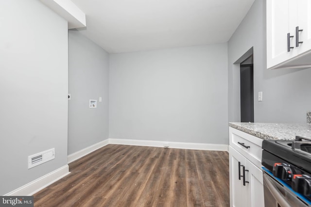 kitchen featuring dark wood-type flooring, light stone countertops, stainless steel stove, and white cabinets