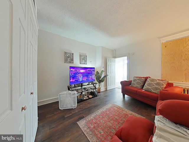 living room featuring a textured ceiling, dark wood-type flooring, and baseboards