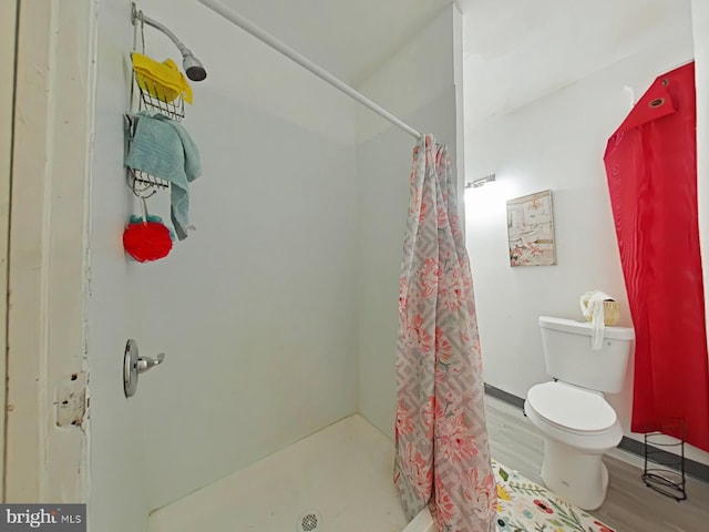 full bathroom featuring toilet, a shower stall, and wood finished floors