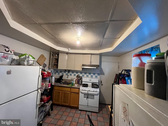 kitchen featuring white appliances, decorative backsplash, a paneled ceiling, dark tile patterned floors, and a raised ceiling