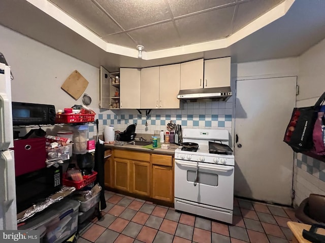 kitchen with tasteful backsplash, a raised ceiling, dark tile patterned flooring, and white gas range oven