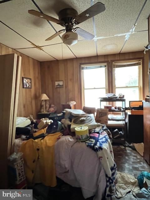 misc room with wood walls, ceiling fan, and a healthy amount of sunlight