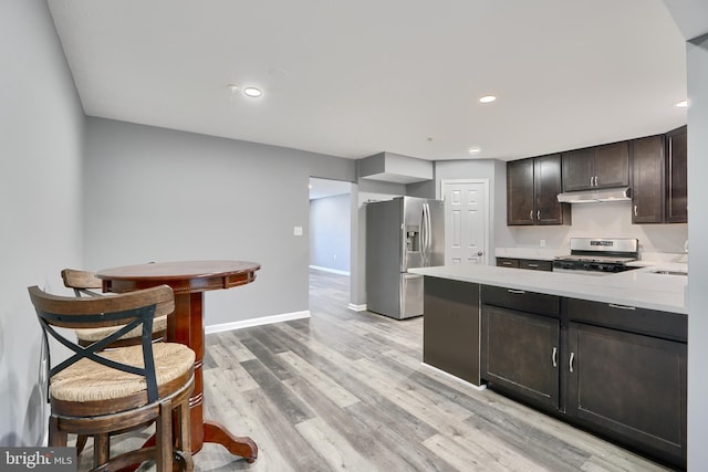 kitchen with stainless steel appliances, dark brown cabinets, and light hardwood / wood-style flooring