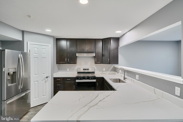 kitchen with appliances with stainless steel finishes, light stone counters, light wood-type flooring, and sink