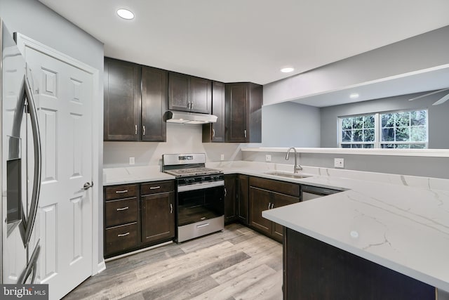 kitchen featuring sink, light stone counters, light hardwood / wood-style floors, stainless steel appliances, and kitchen peninsula