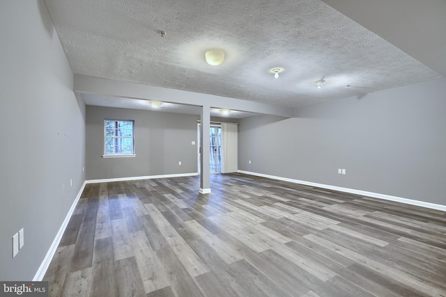 basement featuring wood-type flooring and a textured ceiling