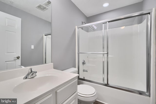 full bathroom featuring combined bath / shower with glass door, toilet, and vanity