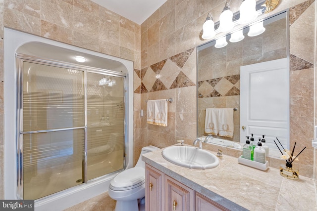 bathroom with vanity, tile walls, a shower with shower door, and toilet