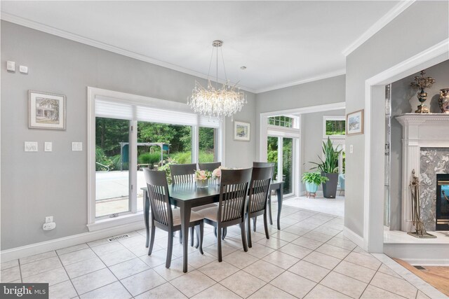 dining room with light tile patterned flooring, a fireplace, a chandelier, and ornamental molding