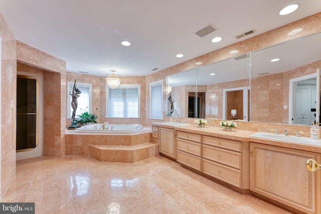 bathroom featuring vanity, tiled bath, and tile walls