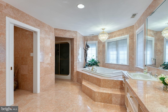 bathroom featuring independent shower and bath, vanity, tile walls, and a chandelier