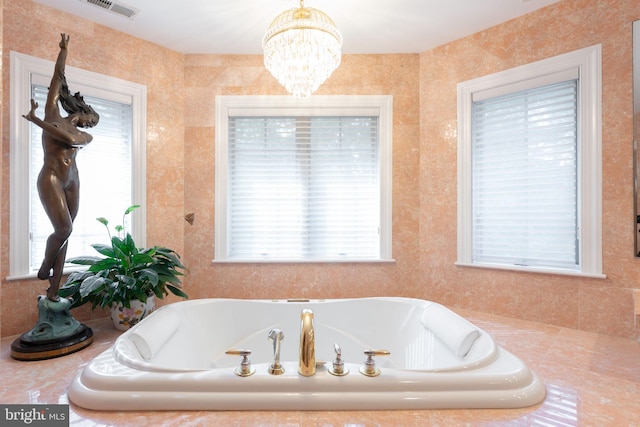 bathroom with tiled tub, a notable chandelier, and a healthy amount of sunlight