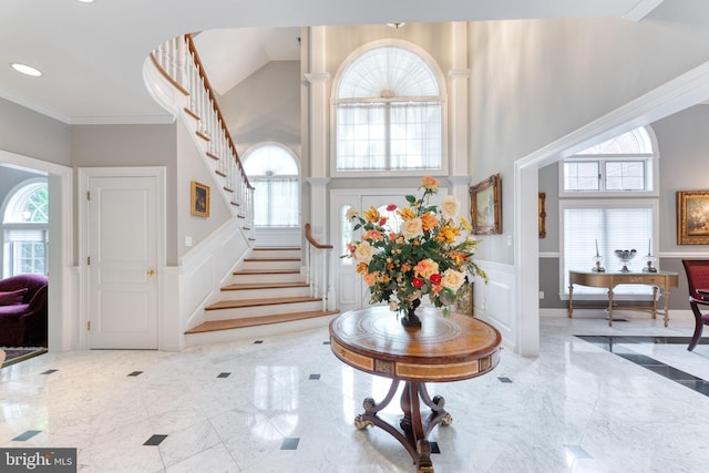 entryway featuring ornamental molding, a wealth of natural light, and a towering ceiling