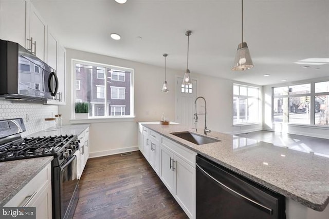 kitchen with hanging light fixtures, sink, dark hardwood / wood-style floors, white cabinetry, and appliances with stainless steel finishes