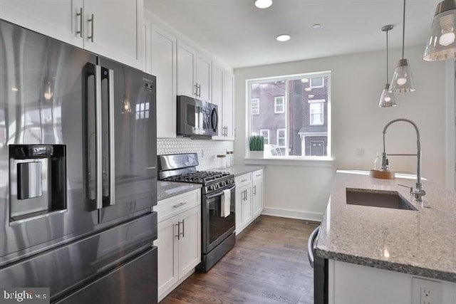 kitchen featuring stainless steel appliances, dark wood-type flooring, sink, white cabinetry, and decorative light fixtures