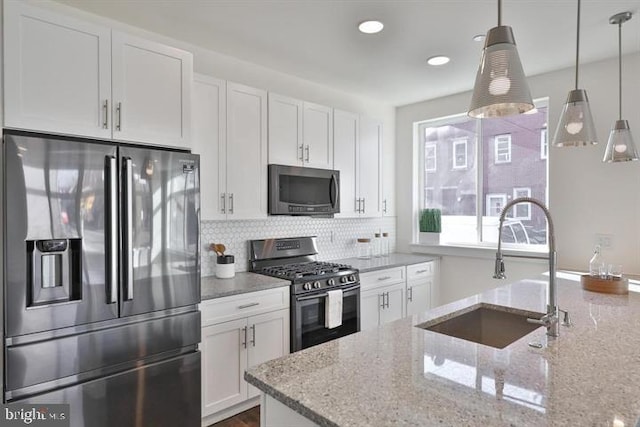 kitchen featuring stainless steel appliances, hanging light fixtures, white cabinets, and sink